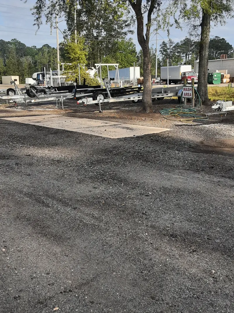 A boat and trailer are parked in the lot of Matthews Boat and RV Storage facility.